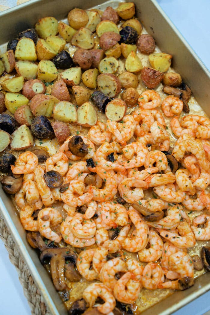 Roasted shrimp and potatoes, paired with savory mushrooms, all seasoned to perfection in a rectangular baking pan.