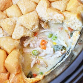 Close-up of a creamy Chicken Pot Pie with vegetables and a golden-brown biscuit topping, partially served&mdash;comfort food made easy in the Crockpot.