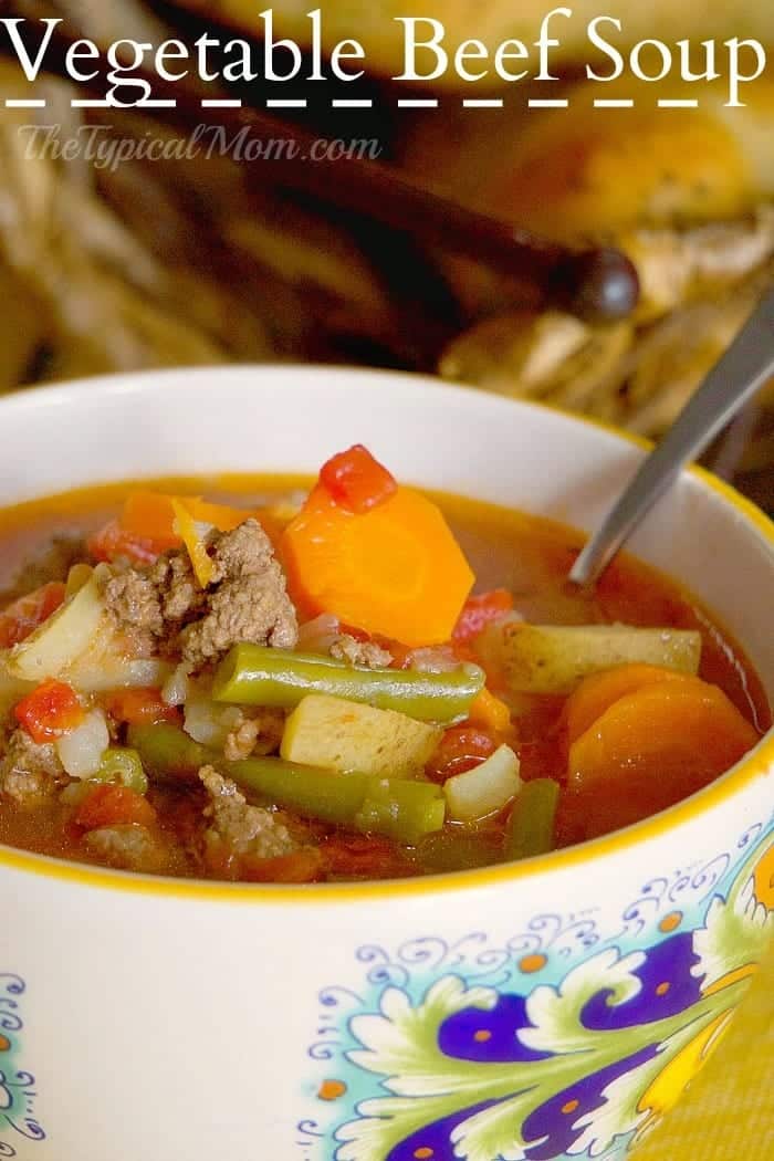 A bowl of vegetable beef soup with carrots, green beans, beef, and tomatoes sits with a spoon in the bowl&mdash;perfect inspiration for leftover meatloaf recipes.