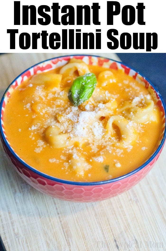 Bowl of creamy tortellini soup topped with grated cheese and basil, on a wooden surface&mdash;perfect for fans of instant pot soup recipes.