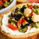 A slice of bread with creamy spread topped with colorful Olive Salad, text reads Muffuletta Recipe.