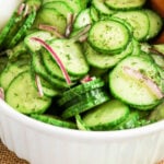 Sliced cucumber and red onion salad with fresh dill in a white bowl, text reads Cucumber Dill Salad.