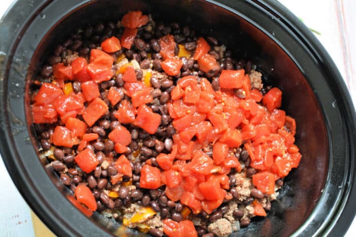 Black beans, ground meat, and diced tomatoes layered in a Crockpot make this Cowboy Casserole an easy and hearty Crockpot recipe ready to be cooked.