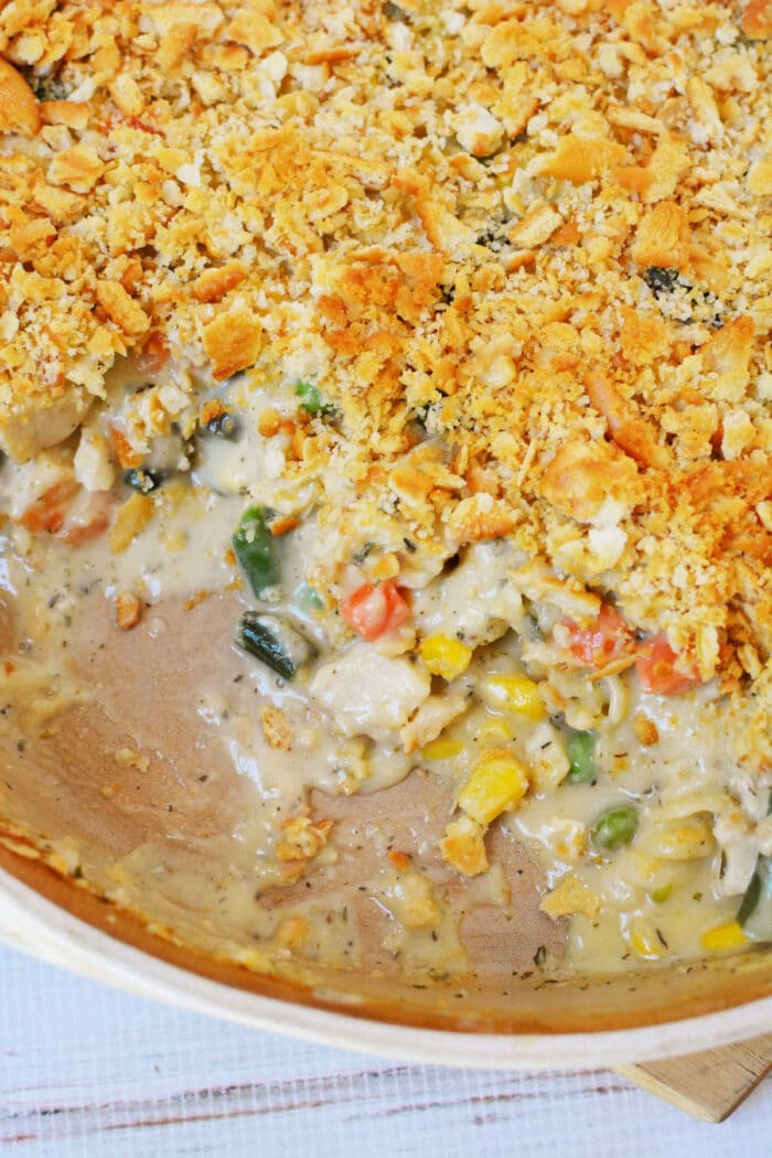 Creamy vegetable casserole with a golden Ritz cracker crumb topping, partially served to reveal the rich filling—similar in comfort to a classic Ritz Chicken Casserole.