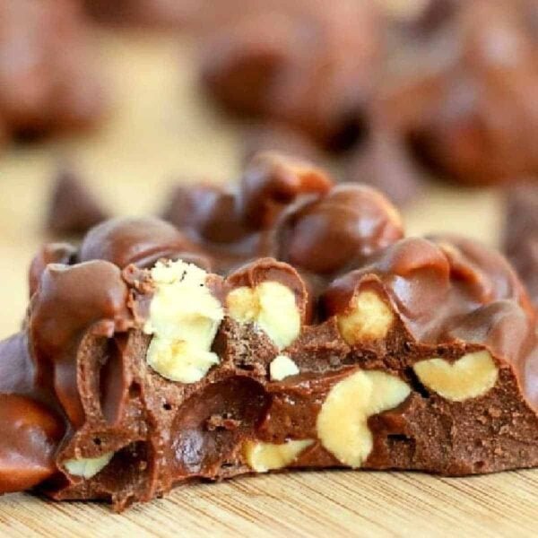 Close-up of crock pot peanut clusters with visible nuts inside, placed on a wooden surface.