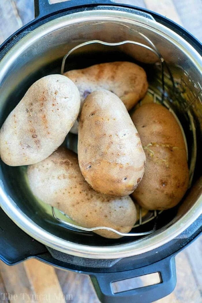 Five unpeeled potatoes sit on a metal rack in the Instant Pot, ready to be transformed into perfectly fluffy instant pot baked potatoes.