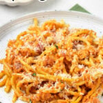 Plate of spaghetti with pumpkin sauce and grated cheese, text above reads Pumpkin Spaghetti—a delicious Pumpkin Pasta dish perfect for cozy autumn dinners.