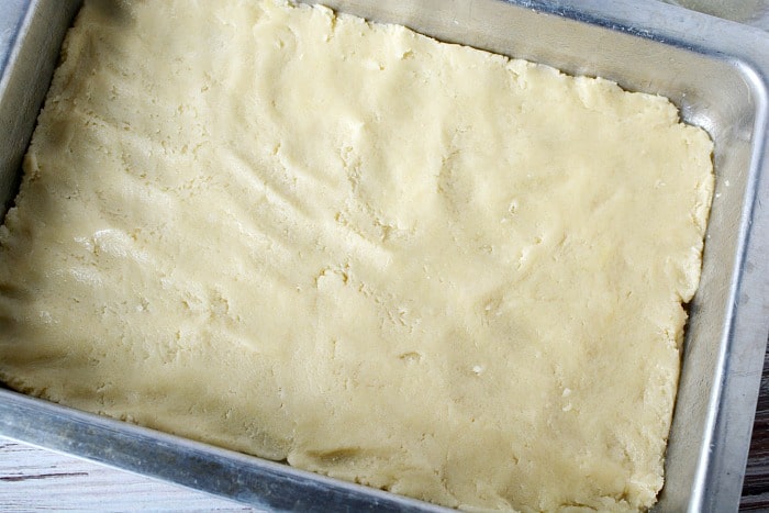 Unbaked dough from one of the best boxed cake mix recipes is evenly pressed into a rectangular metal baking pan, ready to be baked.