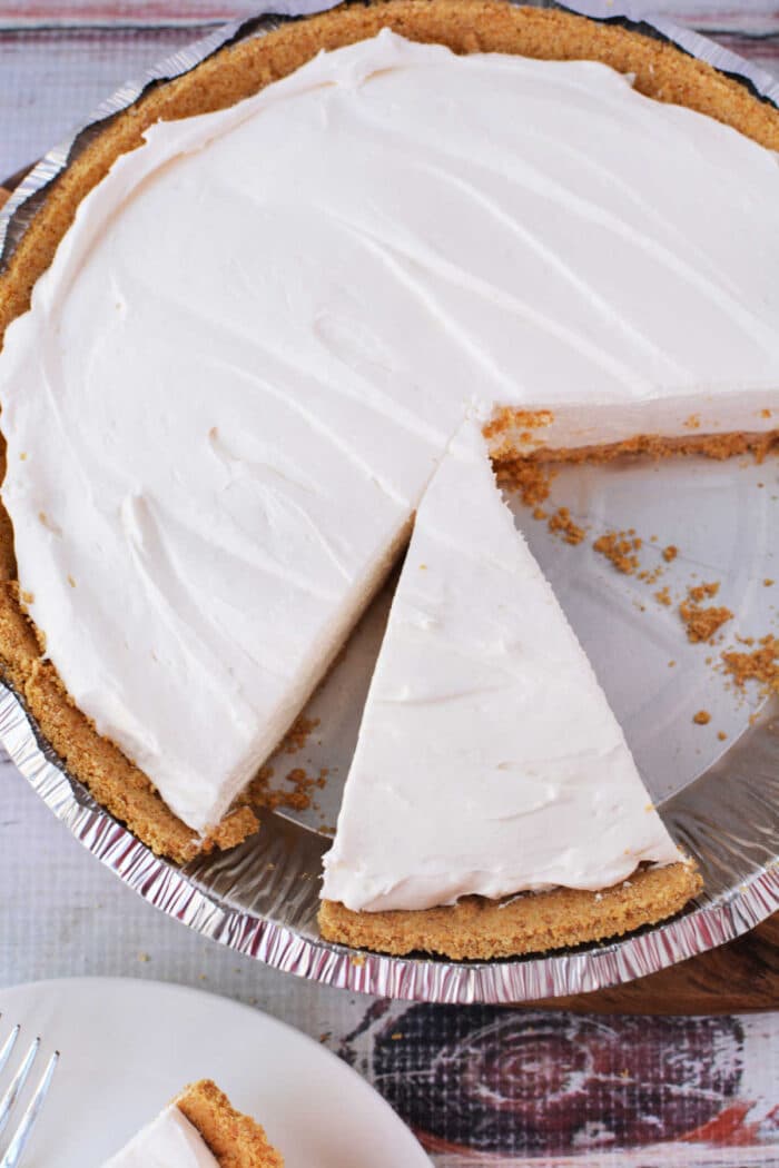 A 3 ingredient cheesecake with a graham cracker crust and one slice removed.