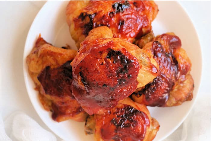 A plate of glazed, roasted chicken thighs, cooked from frozen in an air fryer.